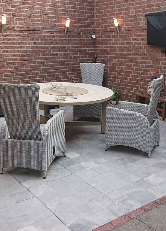 Fertige Terrasse mit Steinplatten, rundem Tisch und Rattan-Sitzgruppe
